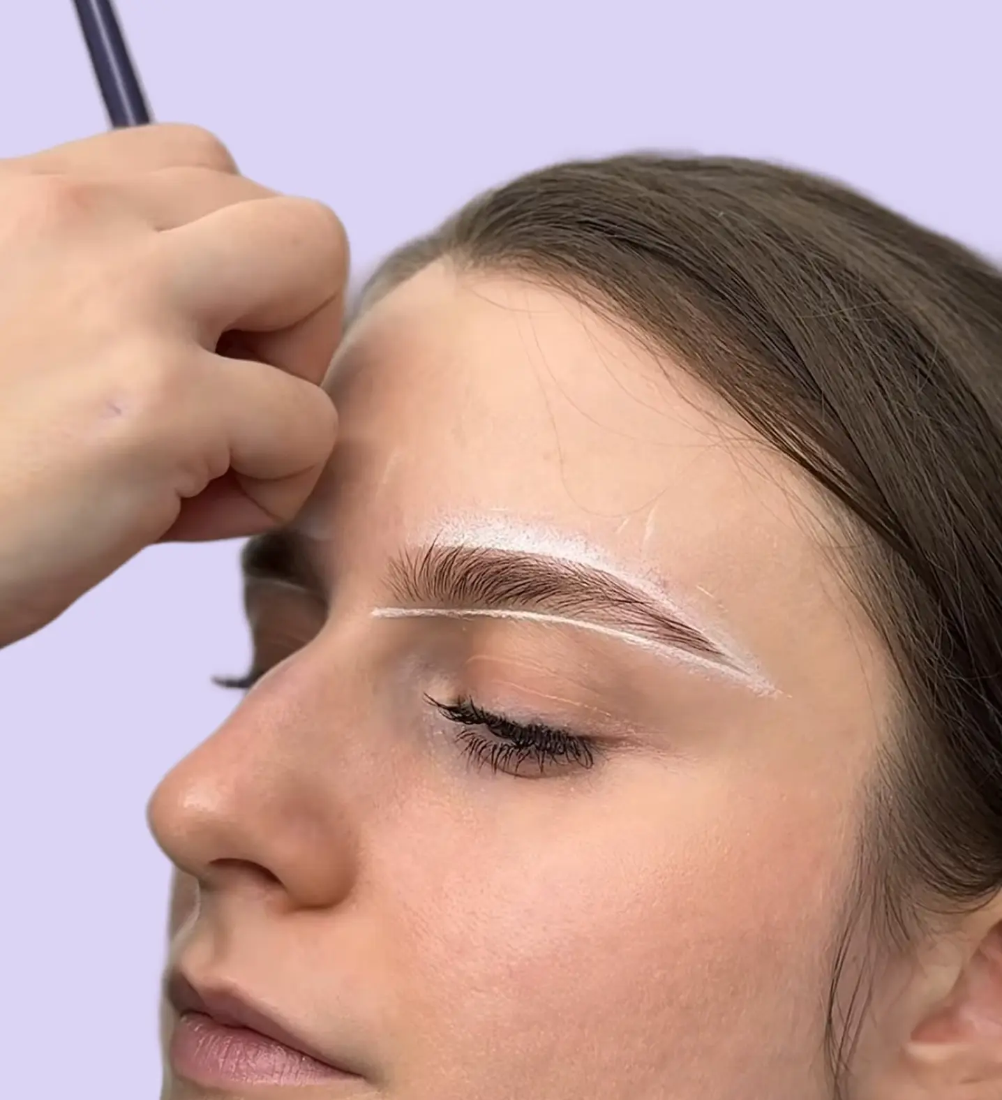 Brow artist conturează forma sprâncenelor unui model, compoziție ce arată serviciul de brows